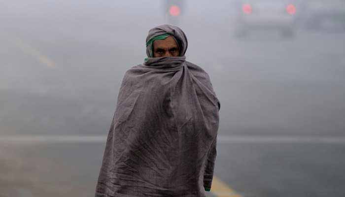 A man covering himself up with warm clothes due to severe cold. — AFP/File