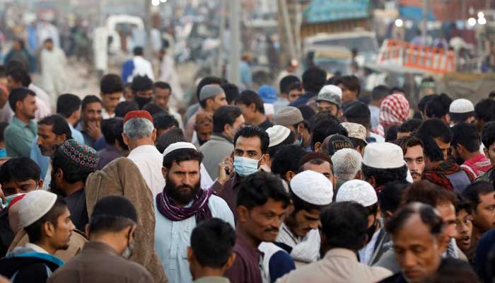 A man wearing a protective mask walks through a crowd of people along a makeshift market in Karachi. — Reuters/File