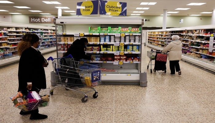 People shop next to the clubcard price branding inside a branch of a Tesco Extra Supermarket in London, Britain, February 10, 2022. Picture taken February 10, 2022. — Reuters