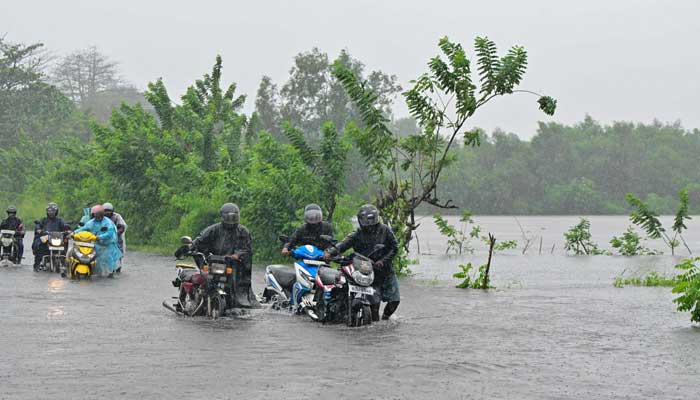 Motorists wade through a flooded street in Biyagama on the outskirts of Colombo on November 28, 2025. — AFP