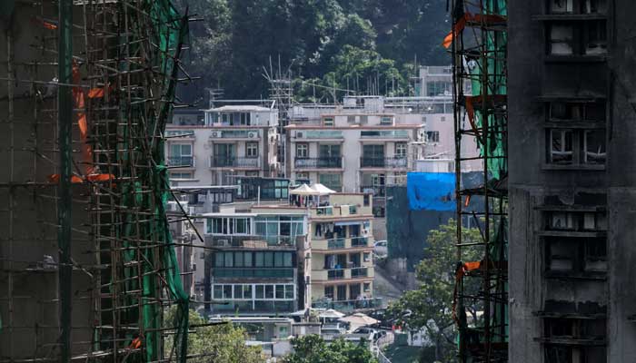 Buildings stand in the background as seen between the bamboo scaffolding on charred buildings of Wang Fuk Court housing complex following a deadly fire, in Tai Po, Hong Kong, China November 28, 2025. — Reuters