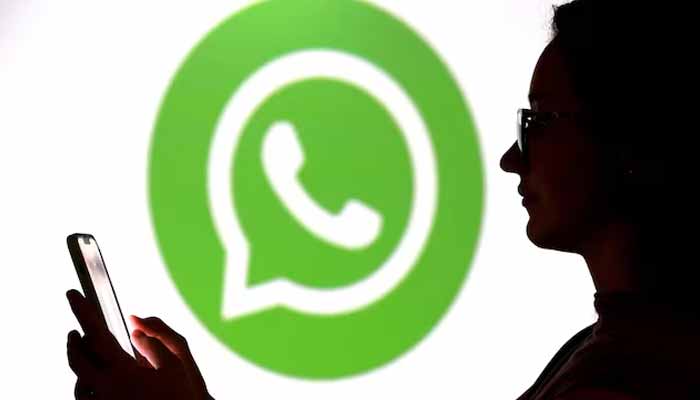 A teenager poses for a photo while holding a smartphone in front of a Whatsapp logo in this illustration taken September 11, 2025. — Reuters