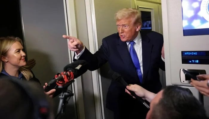 US President Donald Trump speaks to reporters as White House Press Secretary Karoline Leavitt stands by aboard Air Force One on his return to Washington, DC, March 9, 2025. — Reuters