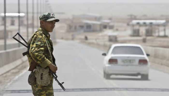 A frontier guard stands on a bridge to Afghanistan across Panj river in Panji Poyon border outpost, south of Dushanbe, Tajikistan, May 31, 2008. — Reuters