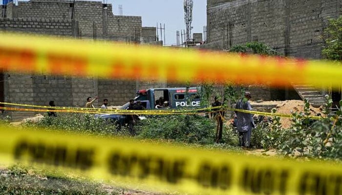 Representational image of residents gathered at a crime scene as police personnel inspect a site cordoned off with barricade tapes in Karachi on May 8, 2025. — Reuters