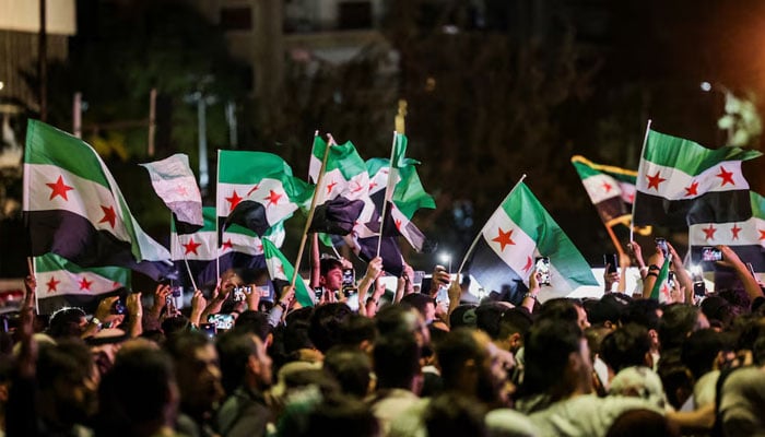 People wave Syrian flags as they gather at Umayyad Square in Damascus to watch a broadcast of Syrian President Ahmed Al-Sharaa delivering a speech at the United Nations, in Syria on September 24, 2025. — Reuters