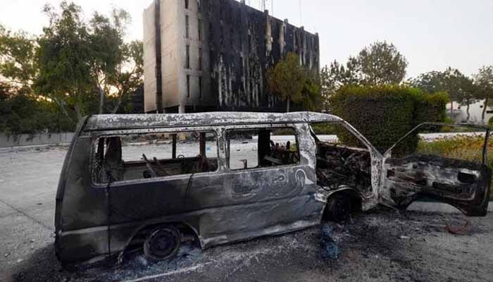 Smoke billows from a Radio Pakistan building next to a burnt vehicle after it was set afire by the supporters of Pakistans former Prime Minister Imran Khan during a protest against his arrest, in Peshawar, May 10, 2023. — Reuters