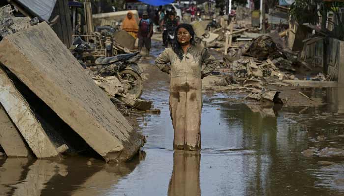 A woman covered in mud stands on a street filled with mud after a flash flood hit the area in Aceh Tamiang, Aceh province on December 6, 2025.— AFP