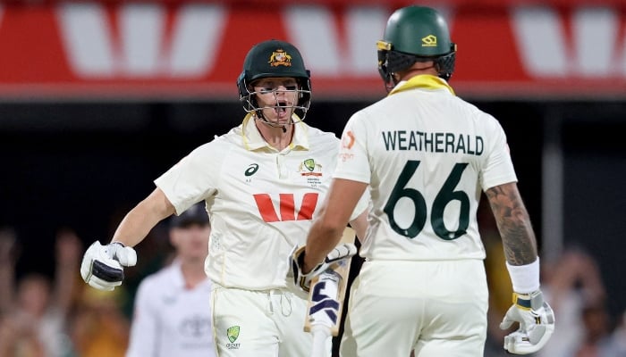 Australias captain Steve Smith (L) celebrates with team mate Jake Weatherald after hitting the winning runs on day four of the second Ashes cricket Test match between Australia and England at The Gabba in Brisbane on December 7, 2025. — AFP