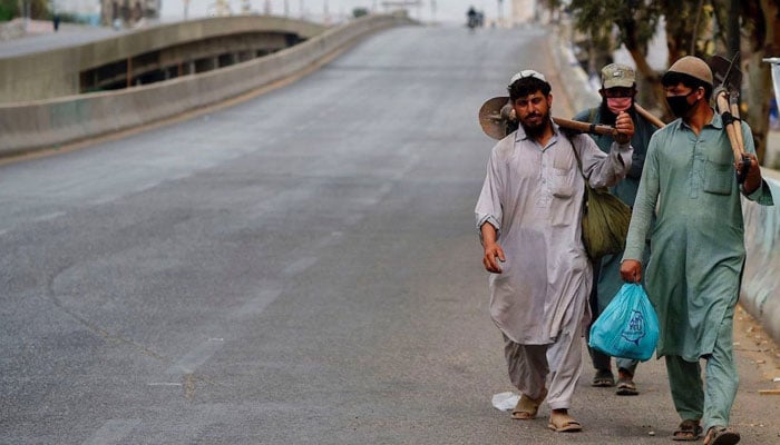 Labourers walk on a deserted road in this undated photo. — AFP/File