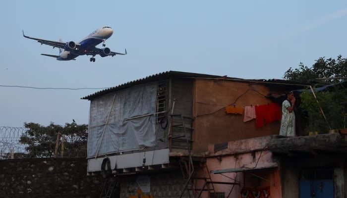 An Indigo flight lands as a woman prays at her house in Mumbai, India, December 6, 2025. — Rueters