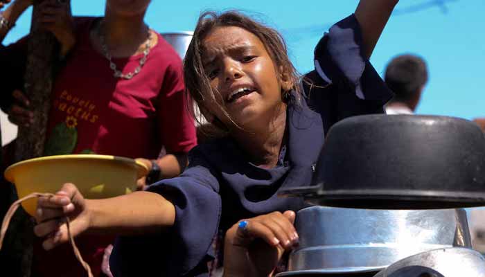 A Palestinian girl gestures as she waits to receive food from a charity kitchen, amid a hunger crisis, in Khan Younis, southern Gaza Strip, August 4, 2025. — Reuters