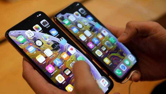 The image shows a person holding smartphones. — Reuters/File