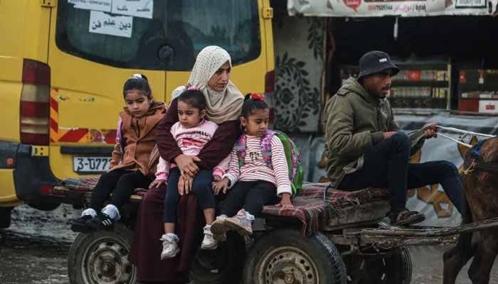 A woman takes her children to school on a horse cart in Deir el-Balah, in the central Gaza Strip, on December 10, 2025. — AFP