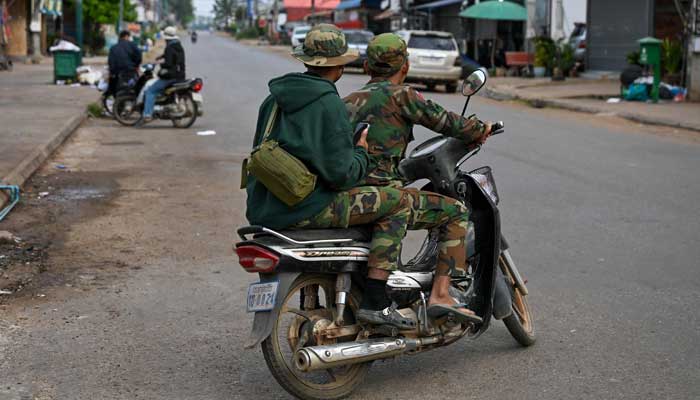 Soldiers ride a motorcycle along a street in Oddar Meanchey province on December 10, 2025. — AFP