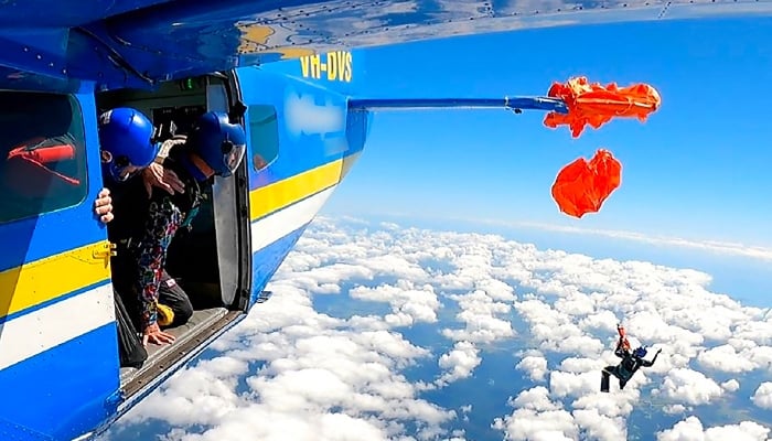 This frame grab taken from undated video footage provided by the Australian Transport Safety Bureau on December 11, 2025, shows the moment a skydiver was left dangling thousands of metres in the air after their parachute caught on the planes tail. — AFP