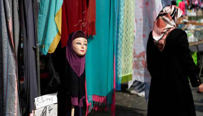 A woman walks past a mannequin wearing an hijab headscarf at a market in the Brussels district of Molenbeek, Belgium.— Reuters/File