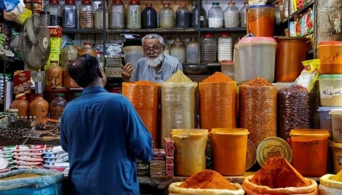 A shopkeeper speaks with a customer while selling spices at a market in Karachi, June 11, 2024.— Reuters