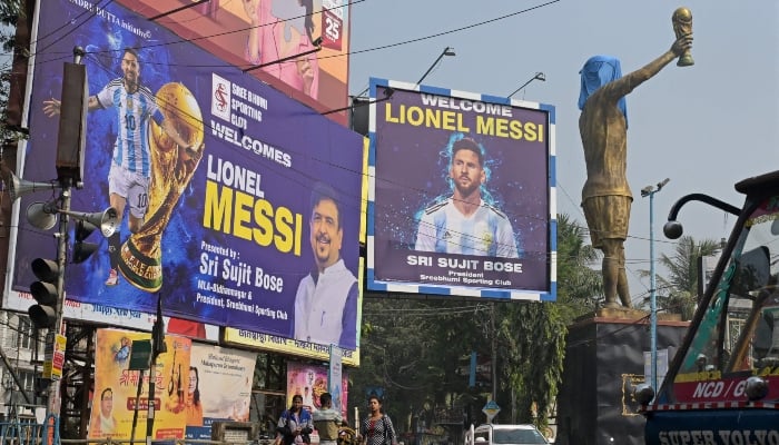Commuters cross promotional posters and veiled statue of Inter Miamis Argentine forward #10 Lionel Messi, on the eve of his visit, in Kolkata, India, on December 12, 2025. — AFP