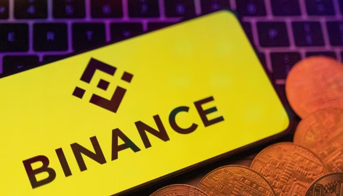 Smartphone with displayed Binance logo and representation of cryptocurrencies are placed on a keyboard in this illustration. — Reuters/File
