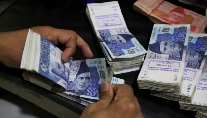 An employee counts Pakistani rupee notes at a bank in Peshawar, Khyber Pakhtunkhwa. — Reuters/File
