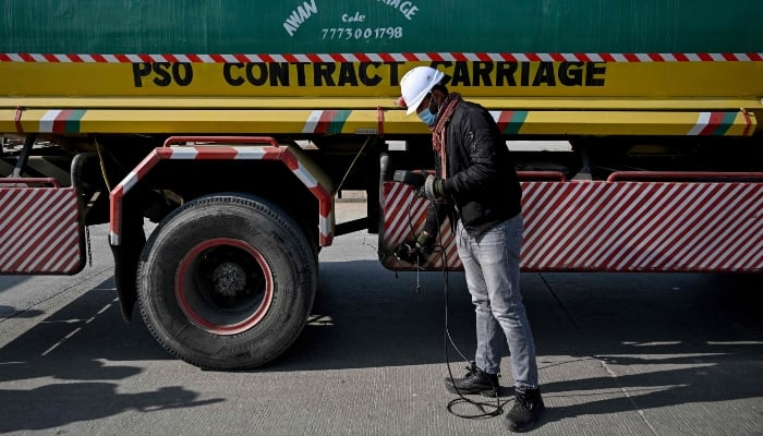 This picture taken on December 10, 2025, shows technician Waleed Ahmed examining a vehicle to test its emissions on road, on the outskirts of Islamabad. — AFP