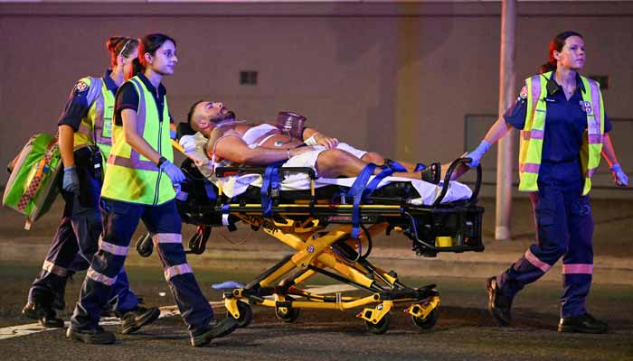 Health workers move a man on a stretcher to an ambulance after a shooting incident at Bondi Beach in Sydney on December 14, 2025. — AFP
