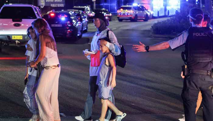 A policeman ushers people across a street after a shooting incident at Bondi Beach in Sydney on December 14, 2025. — AFP