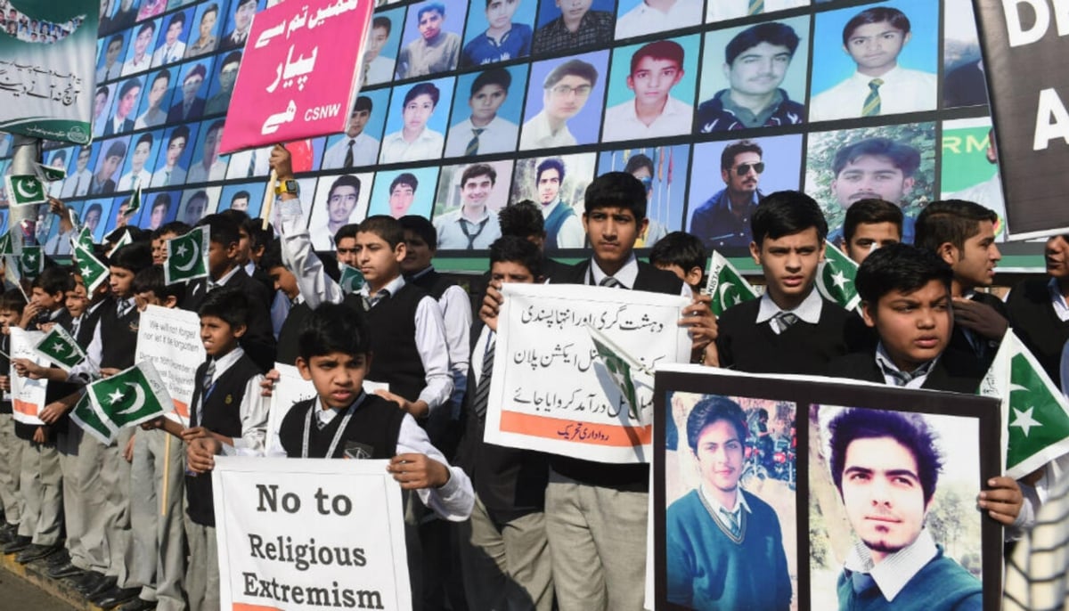 In this photograph, Pakistani students gather near a board displaying photos of the victims of the APS attack. — AFP/File