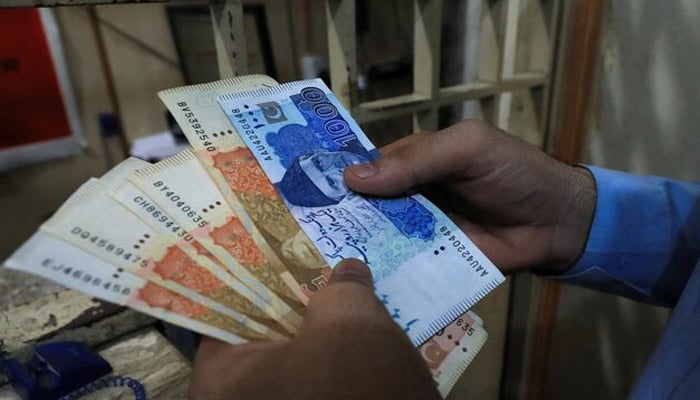 A man counts Pakistani rupee notes at a currency exchange shop in Peshawar, Pakistan on September 12, 2023. — Reuters