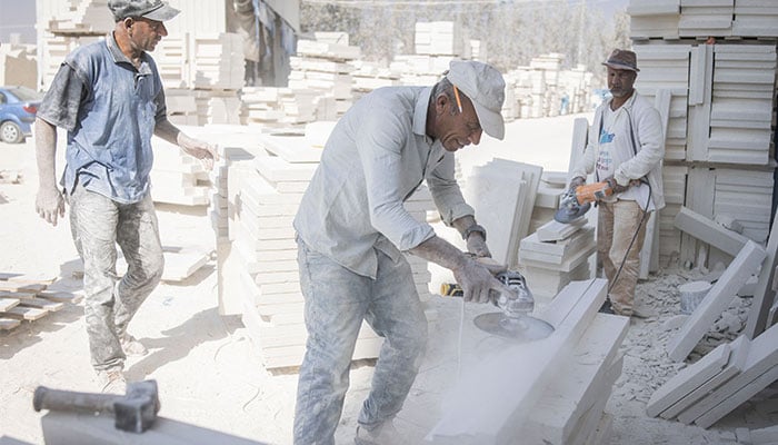 Jamaal (C) who says he has been cutting limestone for 40 years, uses a cutter as his colleagues look on at a Jerusalem stone cutting factory in Beit Fajar, eight kilometres south of the Israeli-occupied West Bank city of Bethlehem on November 10, 2025. — AFP