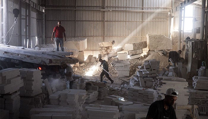 Workers cut and shape a large blocks of Jerusalem stone inside a factory in Beit Fajar, eight kilometres south of the Israeli-occupied West Bank city of Bethlehem on November 10, 2025. — AFP