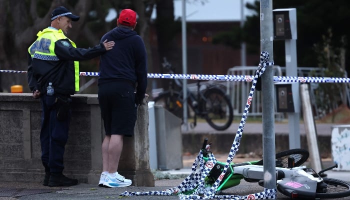 A police officer comforts a member of the Jewish community at the scene of a shooting at Bondi Beach in Sydney on December 15, 2025. — AFP