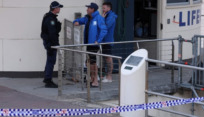 A police officer speaks with lifeguards at the scene of a shooting at Bondi Beach in Sydney on December 15, 2025. — AFP