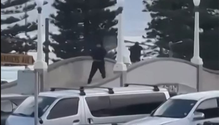 This screen grab made from UGC handout video footage courtesy of Timothy Brant-Coles shows two gunmen dressed in black firing multiple shots on a bridge at Bondi Beach in Sydney on December 14, 2025. — AFP