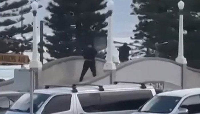 This screen grab made from UGC handout video footage courtesy of Timothy Brant-Coles shows two gunmen dressed in black firing multiple shots on a bridge at Bondi Beach in Sydney on December 14, 2025. — AFP