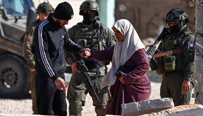 Residents of the Nur Shams refugee camp walk past Israeli security forces as they return to collect belongings ahead of the Israeli military demolition of residential buildings in the camp near Tulkarem in the Israeli-occupied West Bank on December 17, 2025. — AFP