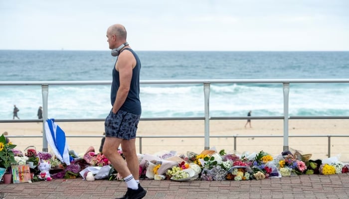 A man walks along the promenade at Bondi Beach, while looking at a floral tribute to honour the victims of a mass shooting targeting a Hanukkah celebration on Sunday at Bondi Beach, in Sydney, Australia, December 16, 2025. — Reuters