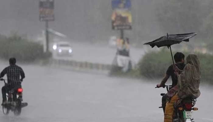 Commuters make way on motorcycles during rain in Punjab. — AFP/File