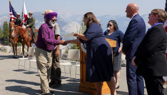 Melissa W Maxim shakes hands and offers a Certificate of Citizenship to a new American citizen at the Glacier Point amphitheatre in Yosemite National Park, California, US, September 17, 2025. — Reuters