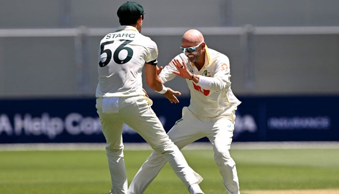 Australian bowler Nathan Lyon (right) celebrates with Mitchell Starc after dismissing England batsman Ben Duckett on the second day of the third Ashes cricket Test match between Australia and England at the Adelaide Oval in Adelaide on December 18, 2025. — AFP