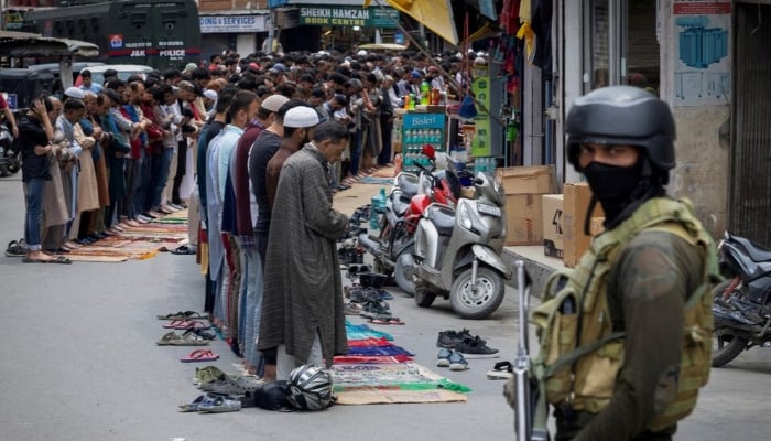 Kashmiri muslims offer Friday prayers on a road as an Indian occupation force personnel stands guard, in Srinagar, IIOJK, on May 2, 2025. — Reuters