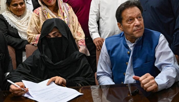 PTI founder-chairman Imran Khan and his wife Bushra Bibi are pictured while signing surety bonds for bail in various cases, at a registrar office in the Lahore High Court on July 17, 2023. — AFP