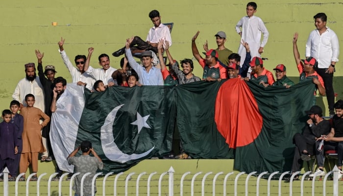 Representational image of spectators holding Pakistan’s and Bangladesh’s national flags cheer during a cricket match between the two countries in Rawalpindi on August 21, 2024. — AFP