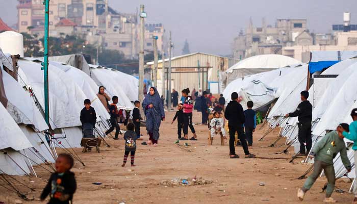 People walk amid shelters at the Nuseirat camp for displaced Palestinians in the central Gaza Strip on December 22, 2025. — AFP