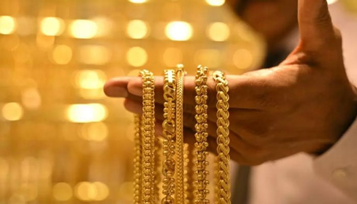 A salesman displays gold chains at a jewellery store. — AFP/File