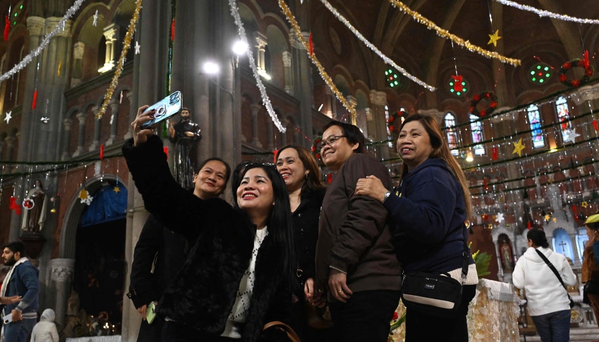 Christians click selfies during Christmas celebrations at Sacred Heart Cathedral in Lahore on December 25, 2025. — AFP