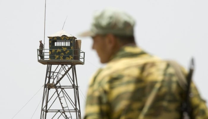 A frontier guard stands on a bridge to Afghanistan across Panj river in Panji Poyon border outpost, south of Dushanbe, Tajikistan. — Reuters/File