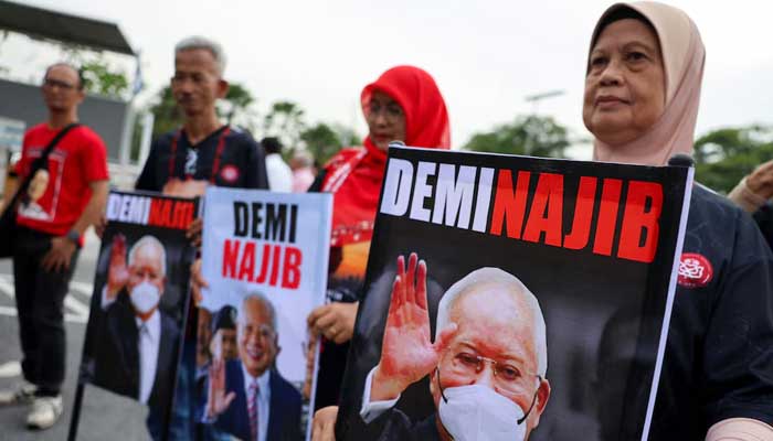 Supporters of former Malaysian PM Najib Razak hold banners featuring his portrait outside the Palace of Justice, in Putrajaya, Malaysia on December 26, 2025. — Reuters
