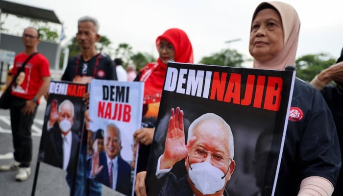 Supporters of former Malaysian Prime Minister Najib Razak hold banners featuring his portrait outside the Palace of Justice in Putrajaya, Malaysia, December 26, 2025. — Reuters